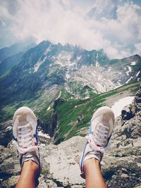 Woman standing on mountain against cloudy sky