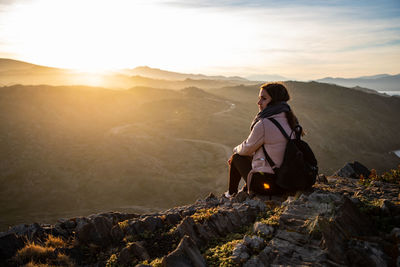 Beautiful women sitting on a rock during sunset on the mountains with copy space