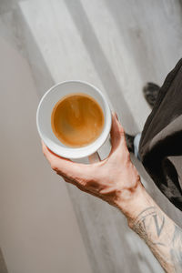 Morning drink, start the day with coffee, barista holds a cup of espresso in his hand, body tattoo