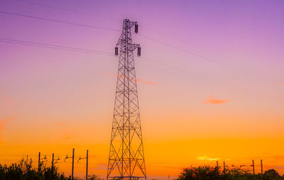 Low angle view of electricity pylon against sky during sunset