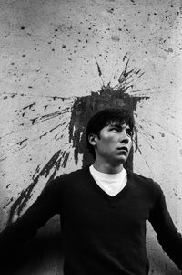 Portrait of young man looking away against wall