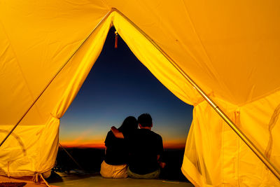 Rear view of man and woman against yellow sky