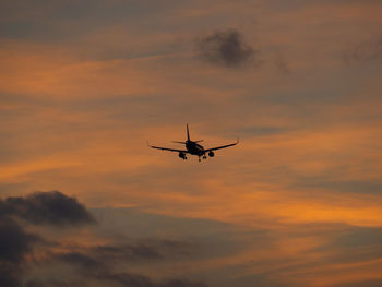 Low angle view of silhouette airplane against sky during sunset