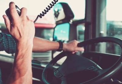 Cropped hand holding radio walkie talkie while driving truck