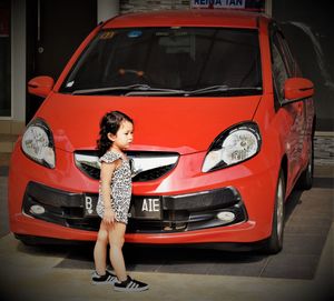 Full length of woman standing on red car