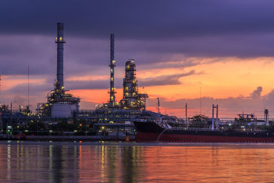 Illuminated factory against sky at sunset