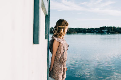 Rear view of woman standing in water against sky