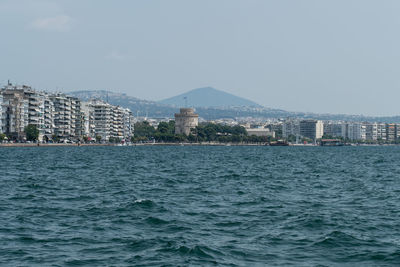 Sea by buildings against sky in city