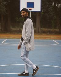 Side view of smiling young man standing on court