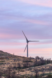 Windmill on field against sky during sunset