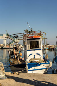 Fishing boat moored at harbor against clear sky
