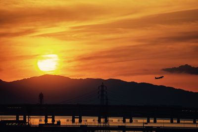 Silhouette bridge over mountains against sky during sunset