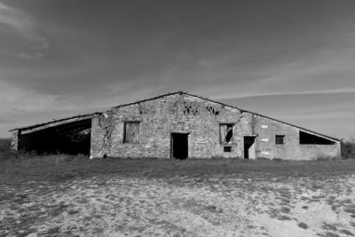 Abandoned house on field against sky