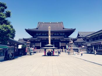 People at temple against clear blue sky