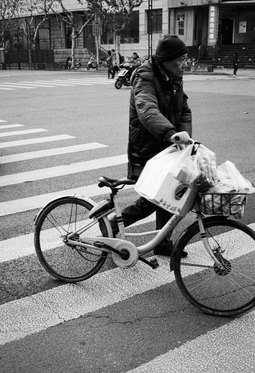 MAN RIDING BICYCLE ON STREET IN CITY