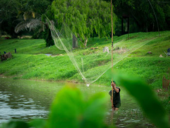 Man holding bamboo standing in lake