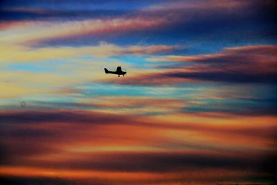 Low angle view of silhouette bird flying against dramatic sky
