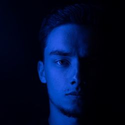 Close-up portrait of young man against black background