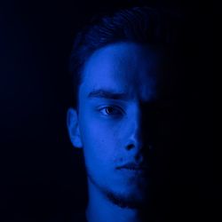 Portrait of man standing against black background