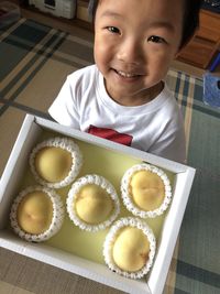 Portrait of happy boy showing fruits in box at home