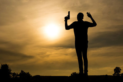 Silhouette man standing against orange sky