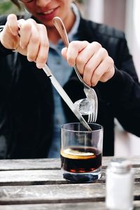 Midsection of woman removing ice cube from drink