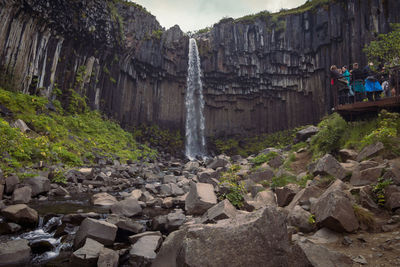 Tourists observing high waterfall landscape photo