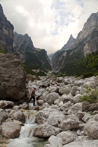 Man on rocks by mountains against sky