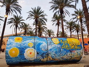 Graffiti on palm trees against blue sky