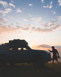 Side view of silhouette woman standing on street during sunset