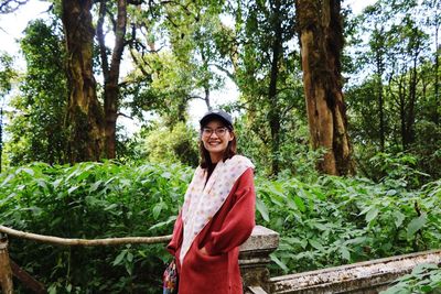 Portrait of smiling young woman standing in forest