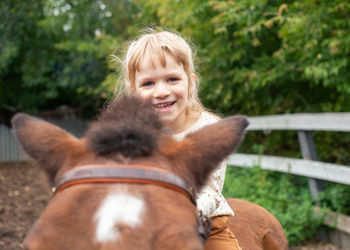 Pretty little girl roding a horse on sunny summer day.