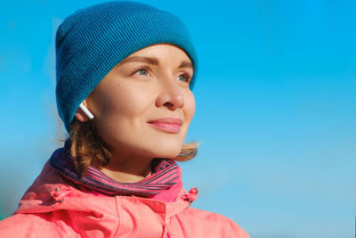 Portrait of a beautiful young woman looking away against blue sky