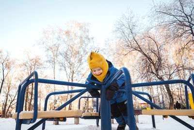 Boy playing with carousel in park during winter