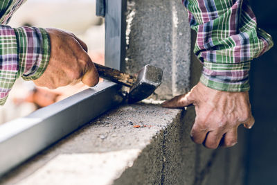 Midsection of man carpenter hammering window 