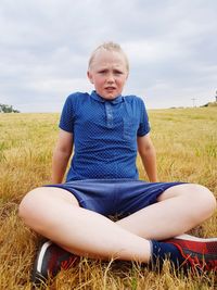 Portrait of cute boy sitting on grassy field