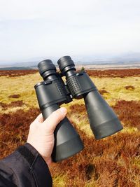 Midsection of person photographing camera on field against sky