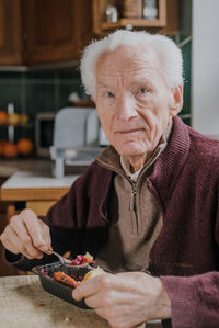 Portrait of senior man eating food at home