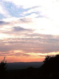 Scenic view of silhouette landscape against orange sky