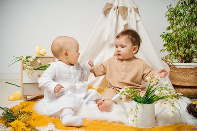 Girl playing with teddy bear while sitting on sofa at home