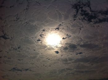 Low angle view of sun shining through clouds