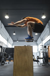 Male athlete jumping over wooden box in gym