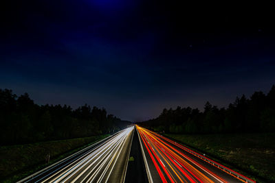 Light trails on highway against sky at night