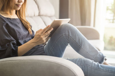 Midsection of woman sitting on sofa at home