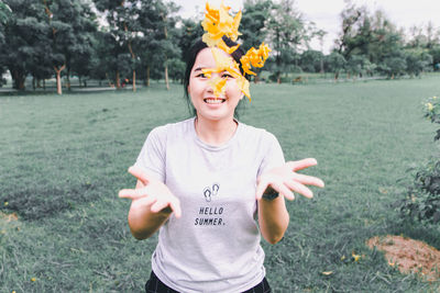 Woman throwing flowers while standing against trees