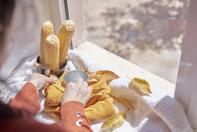 Cropped hand of woman holding coffee cup by window