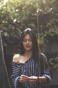 Young woman standing against tree