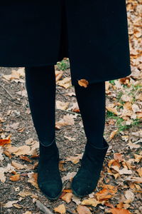 Low section of woman standing on autumn leaves