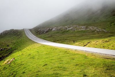 Scenic view of road by mountains against sky