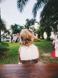 Rear view of woman by palm trees against sky